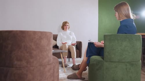 Un invité zoomé parle pendant que le professionnel prend des notes dans une salle de thérapie confortable