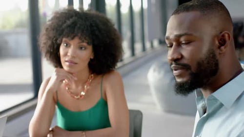 Team of diverse colleagues discussing while sitting together at office