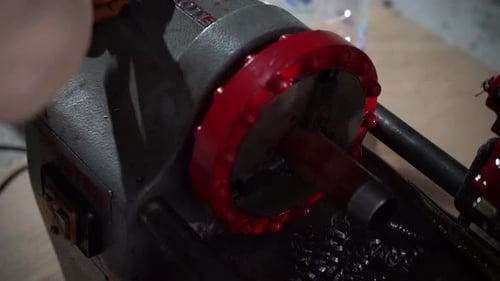 Worker operating a machine for cutting pipes and drilling screw holes in pipes close up