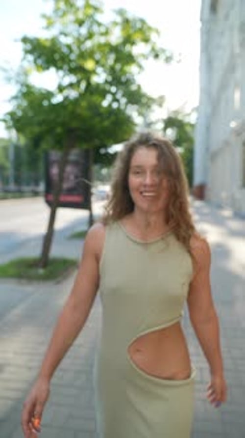 Amidst the Golden Evening Sunlight a Beautiful Girl with Red Curly Hair Wanders Through the City