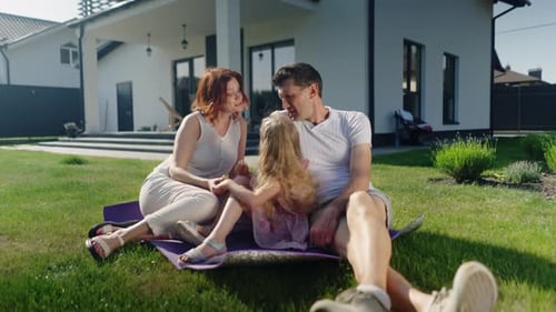 Loving Family Relaxing on Lawn in Backyard