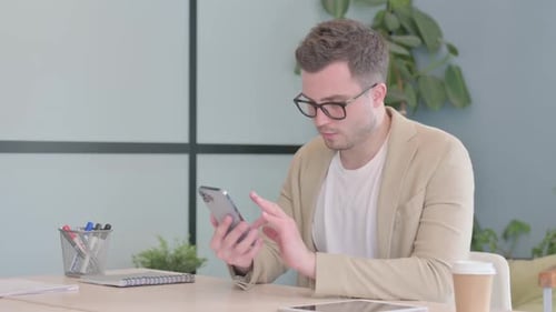 Young Businessman Using Smartphone at Work