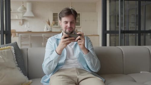 Man Playing Phone Game on Couch Indoors
