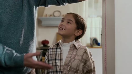 Grandfather Measures Grandchildren's Height at Home