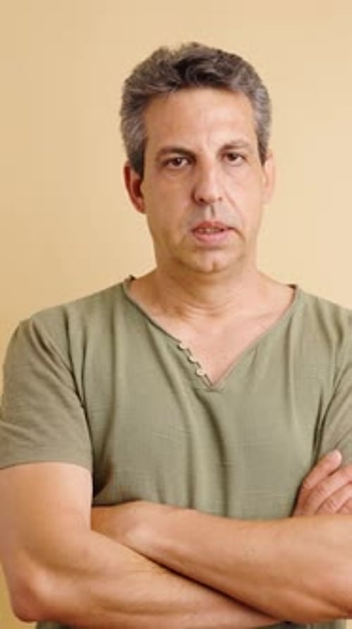 Stern Man Stares with Arms Crossed Indoors