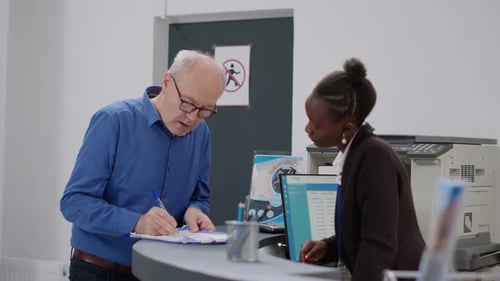 Adult Man Signing Document at Reception Desk