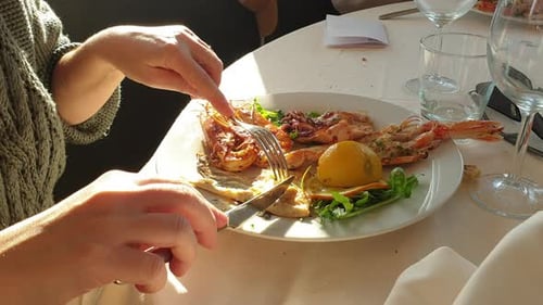 Person Eating Seafood Plate with Knife and Fork