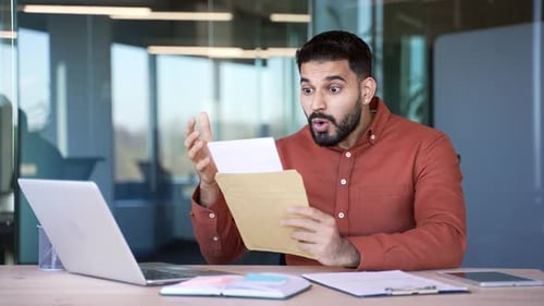 Upset disappointed businessman reading a letter with bad news sitting in a business office. Worried