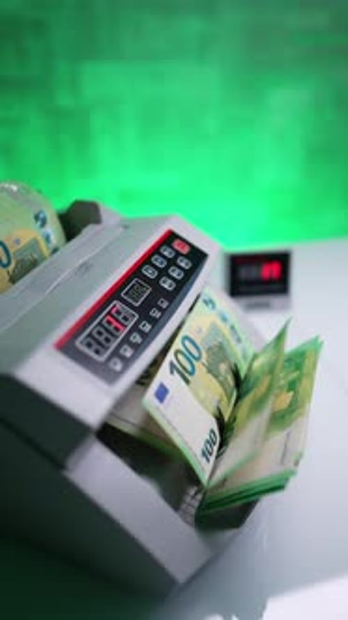 Female hand holding a stack of banknotes in cash counting machine.