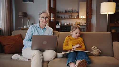 Woman and Child Reading and Using Laptop Indoors