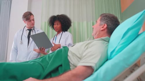 Doctors Reviewing Chart with Patient in Hospital Room
