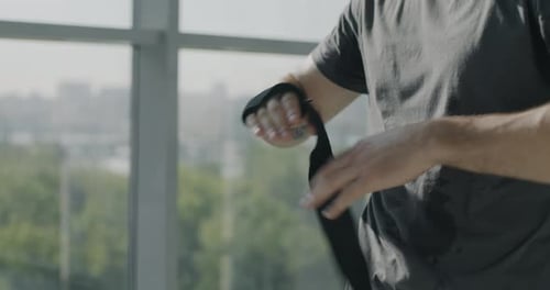 Closeup of Male Hands Wrapping with Straps Preparing for Boxing Training in Gym