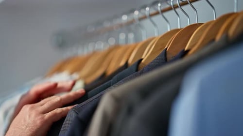 Hand Runs Along Row of Hanging Shirts