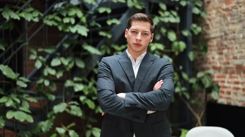 Confident Businessman in Suit Stands with Arms Crossed in a Modern Office