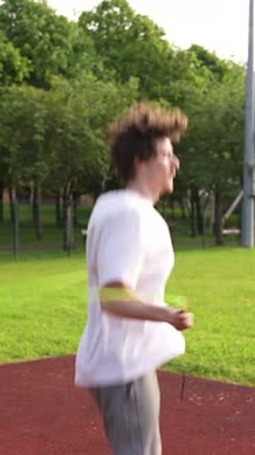 Young Adult Exercising with Jump Rope on Track