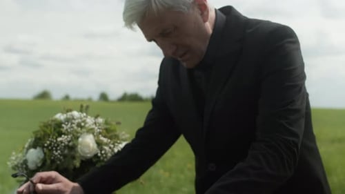Man Mourning at Casket in Rural Field
