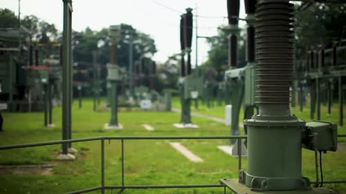 Two engineers inspect equipment at a power substation, shallow focus on foreground