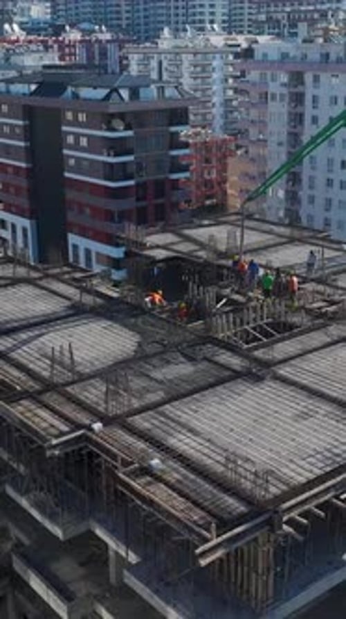 Vertical Video of Engineers Checking Blueprints While Workers Pour Concrete and Assemble Wall