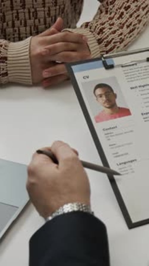 Vertical of Unknown Recruiter Looking through Resume of Positive Young Man
