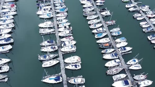 Top down aerial view above luxury yachts parked on turquoise ocean water marina