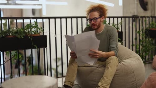 Creative Professional Reviewing Documents on Couch