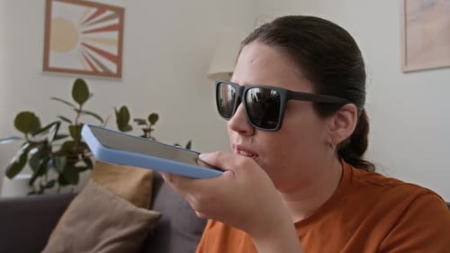 Nahaufnahme eines sehbehinderten Mädchens, das eine Sprachnachricht für einen Freund aufnimmt