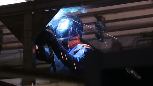 Weld Of Steel Detail Indoors The Plant Close Up. Man Working In Gloves And Protective Wear, Helme...