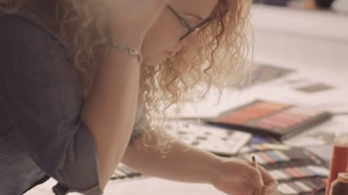 Attractive Fashion Designer Sketching at Table in Her Studio. Woman at Work