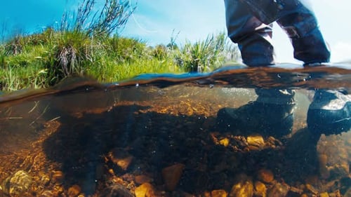 Angler Walks in the River in Wading Boots