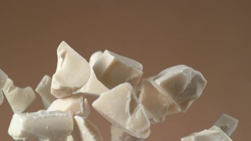 White Chocolate Chunks Floating Against Brown Background