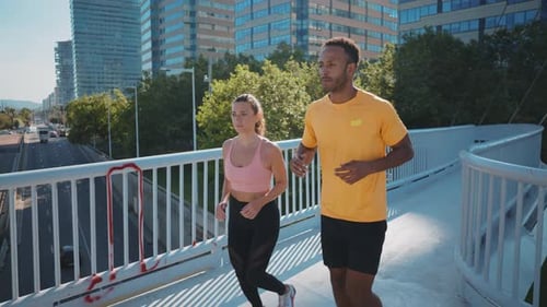 Couple Jogging Across Foot Bridge in City