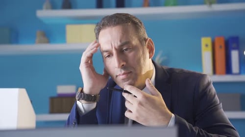 Nahaufnahme eines nachdenklichen Geschäftsmannes, der im Büro mit Laptop arbeitet.