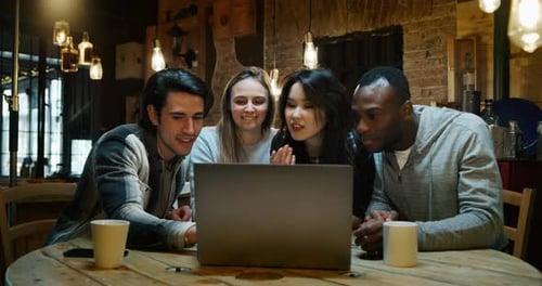 Slow motion of young college friends using a laptop together for study project and drinking tea in