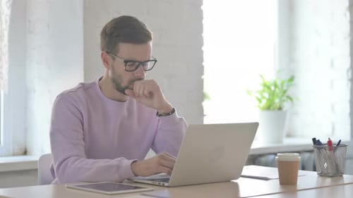 Young Man Working on Laptop in Bright Office