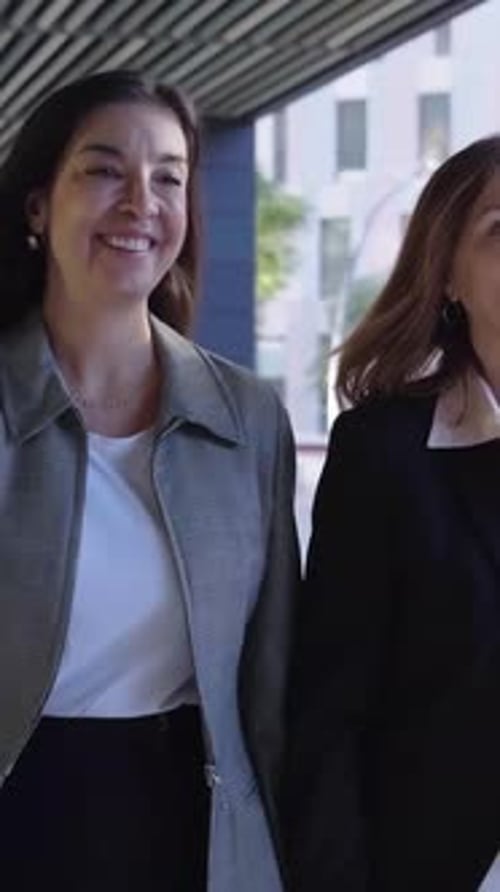 Three Empowered Mature Businesswomen Walk Purposefully in a Hallway Looking Cheerfully and Confident