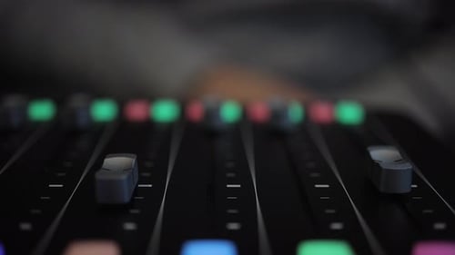 Hand Adjusting Audio Mixer Faders in Studio