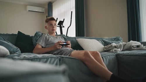 Teenage Boy Relaxing and Playing Video Games at Home