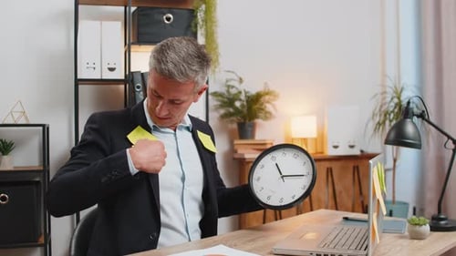 Frustrated Young Businessman in Formal Suit with Clock and Sticky Notes Sitting at Home Office Desk