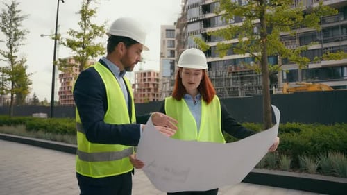 Engineers Discussing Blueprint at Construction Site