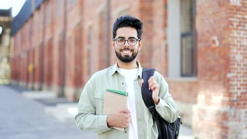 Portrait of happy university student holding books, textbooks looking at camera standing