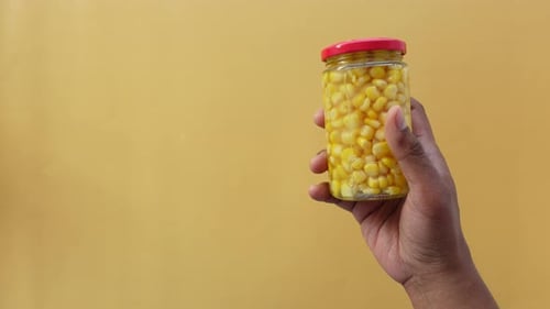 Hand Holding Jar of Preserved Yellow Corn