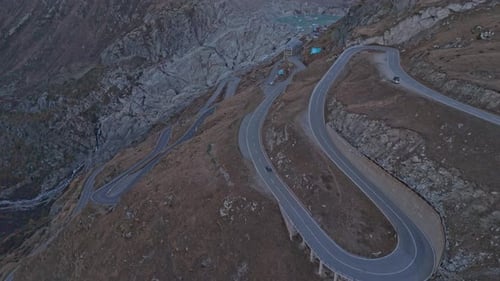 Serpentine Furka Pass road winds through alpine terrain at dawn.