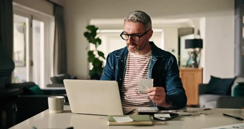 Man Works From Home With Bills and Laptop
