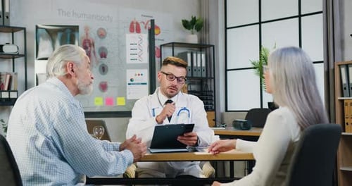 Man doctor in glasses discusses with elderly couple state of health during reception of patients
