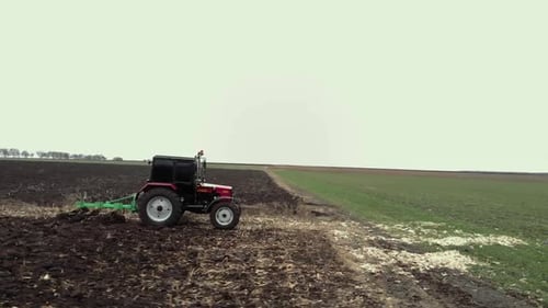 Red tractor plowing the field in Ukraine