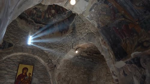 Altgriechische Kirche aus Felsen mit Sonnenlicht, das durch ein einziges Fenster scheint