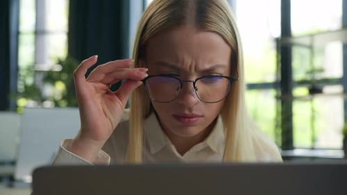 Kaukasische Geschäftsfrau Geschäftsfrau Geschäftsmädchen nimmt Brille ab und schaut verwirrt auf den Laptop-Bildschirm