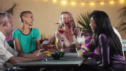 Friends Laughing and Toasting Cocktails at Night