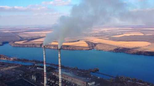 View from the drone at the old aged weathered tall industrial factory chimney with smoke over it.