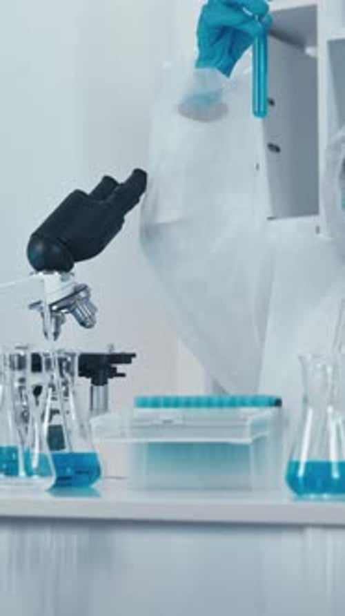 Scientist Working in Laboratory with Microscope and Test Tubes